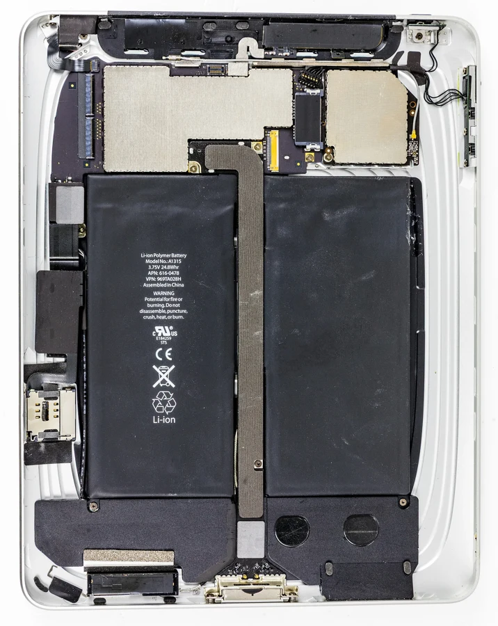 iPad ouvert en atelier, écran retiré, laissant voir les cellules de batterie collées dans le châssis
