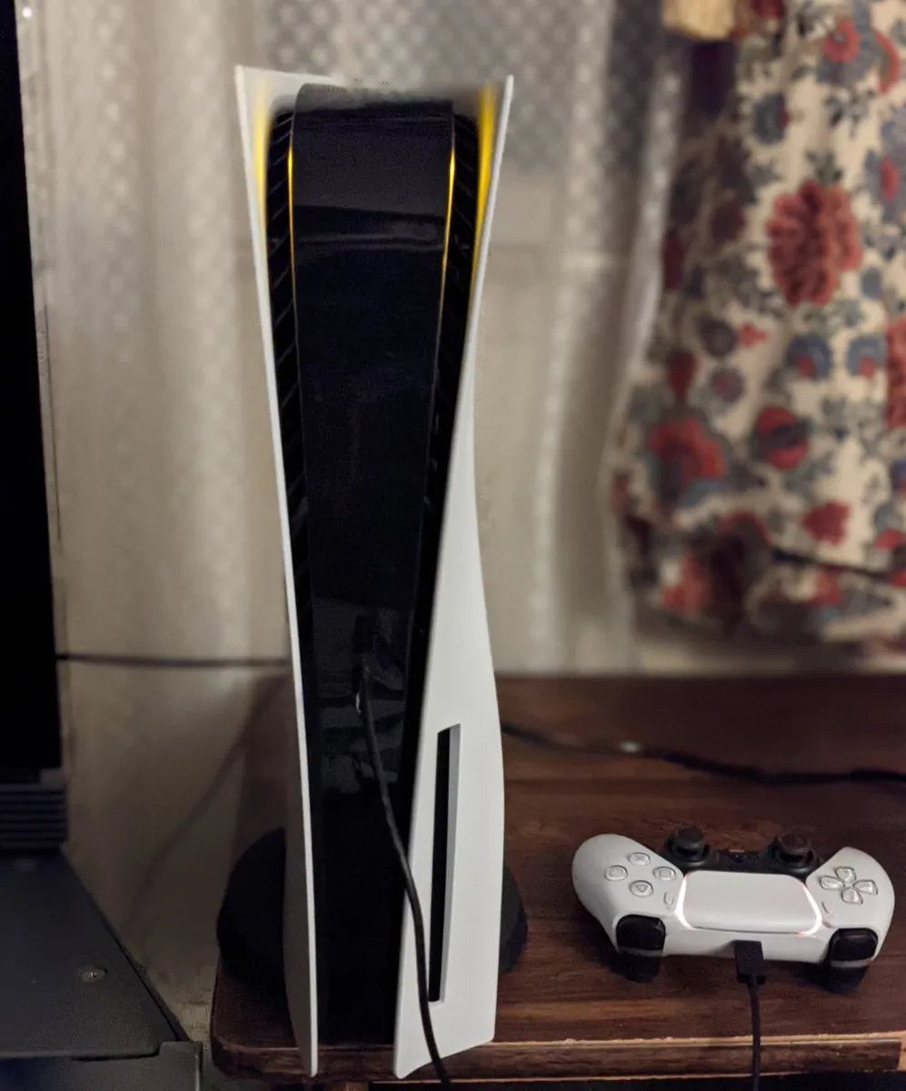 PS5 standard posée à la verticale, fente du lecteur de disque visible en bas de la façade